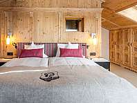 Chambre moderne avec lit double, murs en bois, fenêtre de toit et machine à café