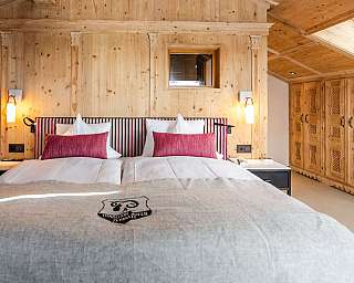 Chambre confortable avec lit double, lambris en bois, armoires et fenêtre de toit.