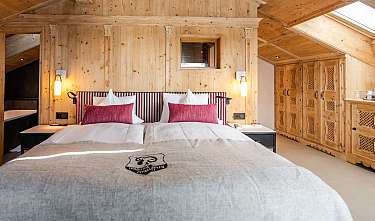 Chambre confortable avec lit double, murs en bois et fenêtre de toit.