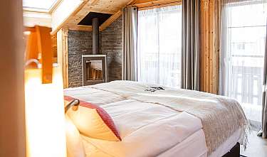 Chambre lumineuse avec lit, cheminée et grandes fenêtres.