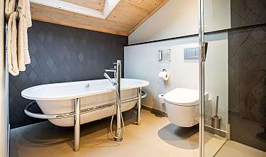 Salle de bain moderne avec baignoire îlot, toilette et douche en verre