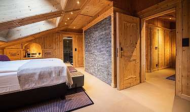 Chambre confortable avec des murs en bois, un lit et un mur d’accent en pierre.