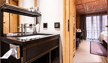 Chambre d'hôtel revêtue de bois avec lavabo et vue sur le lit.