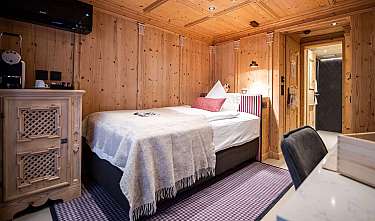 Chambre habillée de bois avec lit, table de chevet et salle de bain ouverte.