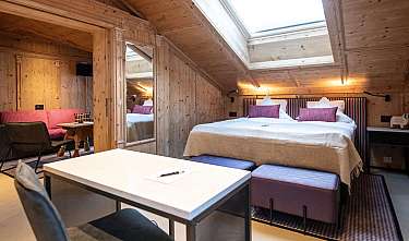Chambre revêtue de bois avec lit double, coin salon et puits de lumière