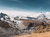 Vaste paysage montagneux avec des glaciers, des rochers escarpés et un ciel bleu.