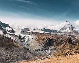 Schneebedeckte Berge, Gletscher und ein klarer Himmel über einer felsigen Landschaft.