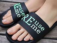 Gros plan sur des pieds en tongs de bain noires avec une inscription turquoise.