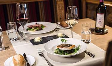 Table de restaurant élégant avec un plat de poisson, du pain, du vin et des verres à eau.