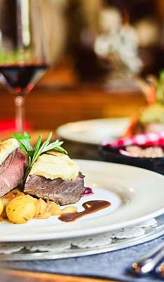 Dresser avec steak, pommes de terre et verres de vin rouge sur une table dressée.