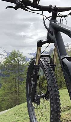 VTT électrique devant des sommets enneigés et une forêt.