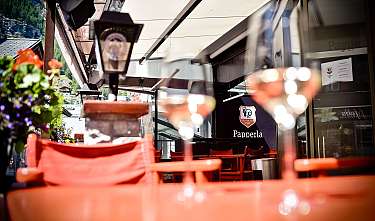 Outdoor terrace with red chairs and blurred glasses in front of a restaurant