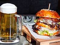 Ein Burger mit Käse, Speck und Salat neben einem gefüllten Bierkrug.