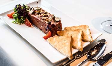 Terrine mit Salat, Tomaten und Toast auf einem weißen Teller