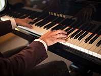 Nahaufnahme von Händen an den Tasten eines Yamaha-Flügels
