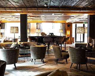 Elegante Lounge mit Sesseln, Couchtischen und warmen Lampen in einem stilvollen Innenraum.