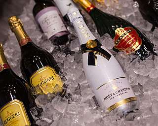 Mehrere Champagnerflaschen liegen in zerstoßenem Eis in einer Kühlwanne.