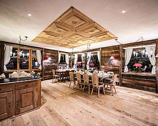Gemütliches Restaurant mit Holzwänden, gedeckten Tischen und dekorativer Holzdecke.
