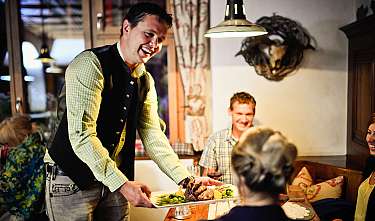 Kellner serviert Gästen in einem Restaurant ein Fleischgericht.