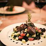 Teller mit Fleisch, Gemüse und Tomaten auf einem elegant gedeckten Tisch