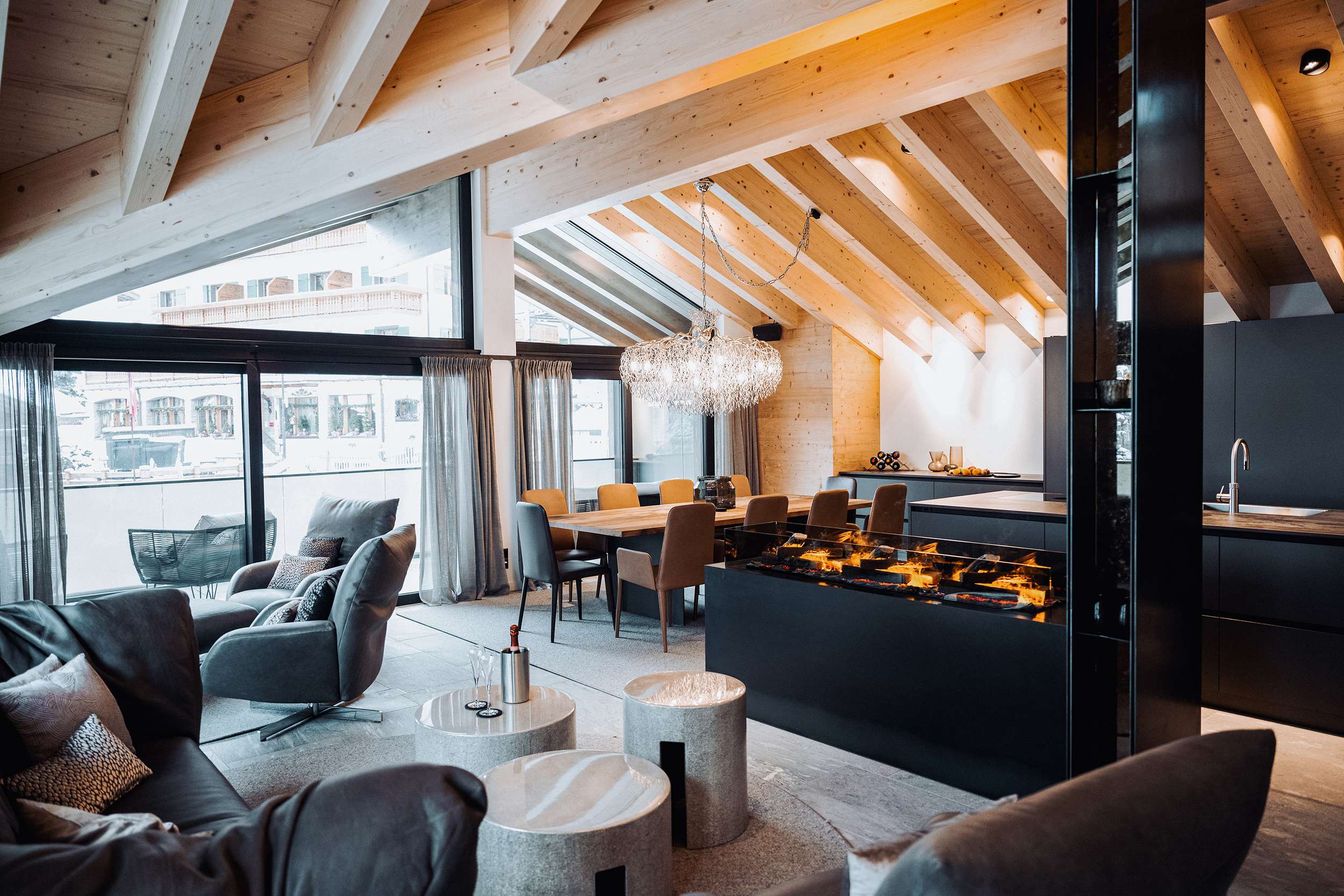 Salon moderne avec plafond en bois, grande baie vitrée, table à manger et cheminée