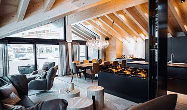 Salon spacieux avec cuisine ouverte, plafond en bois, grandes fenêtres et cheminée