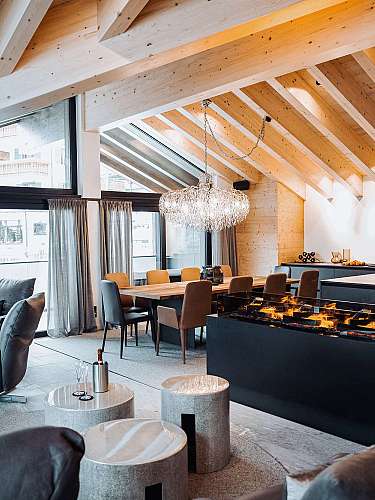 Helles modernes Wohn- und Esszimmer mit Holzdecke, großen Fenstern, Kamin und Esstisch.