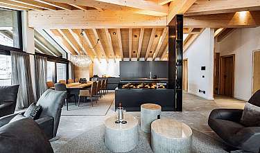 Modernes Wohnzimmer mit Essbereich, Kamin und sichtbaren Holzbalken an der Decke.