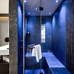 Moderne Duschkabine mit blauen Wänden, Glasabtrennung und einem weißen Handtuch.