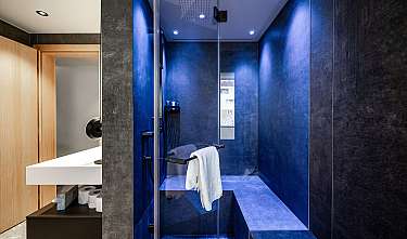 Moderne Dusche mit blauen Wänden, Glasabtrennung und weißem Handtuch im Badezimmerbereich