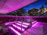 Espace extérieur avec jacuzzi éclairé, escalier et paysage enneigé de nuit