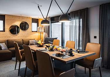 Modernes Esszimmer mit gedecktem Tisch, Holzpaneelwand und großen Pendelleuchten.