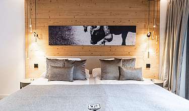 Modernes Schlafzimmer mit Doppelbett, Holzverkleidung, Hängeleuchten und Schwarzweiß-Bild über dem Kopfteil. Ein modernes Schlafzimmer mit Doppelbett, Holzverkleidung uvm.