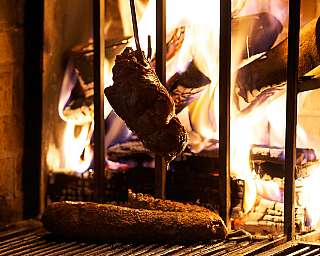Fleischstücke grillen über offenen Flammen in einem Kamin