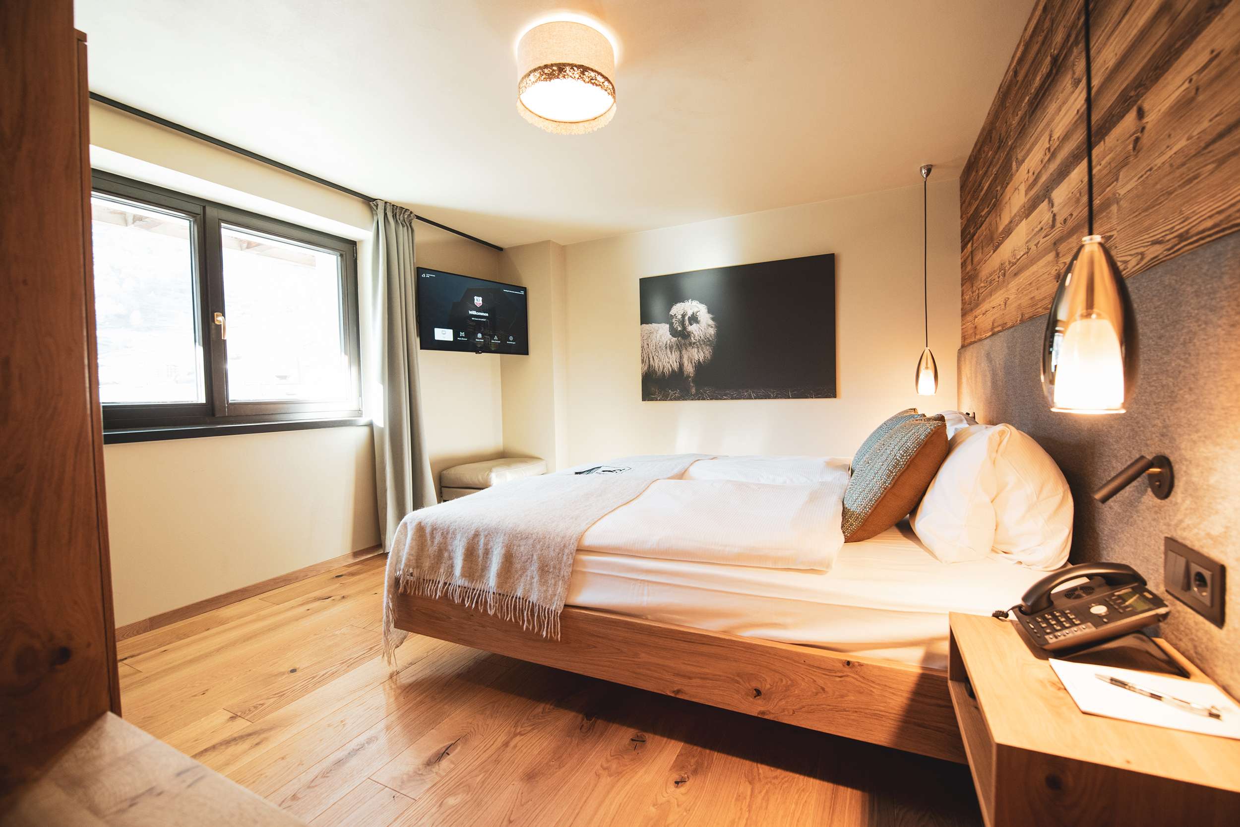 Modern eingerichtetes Schlafzimmer mit Doppelbett, Holzdetails und Wandkunst.