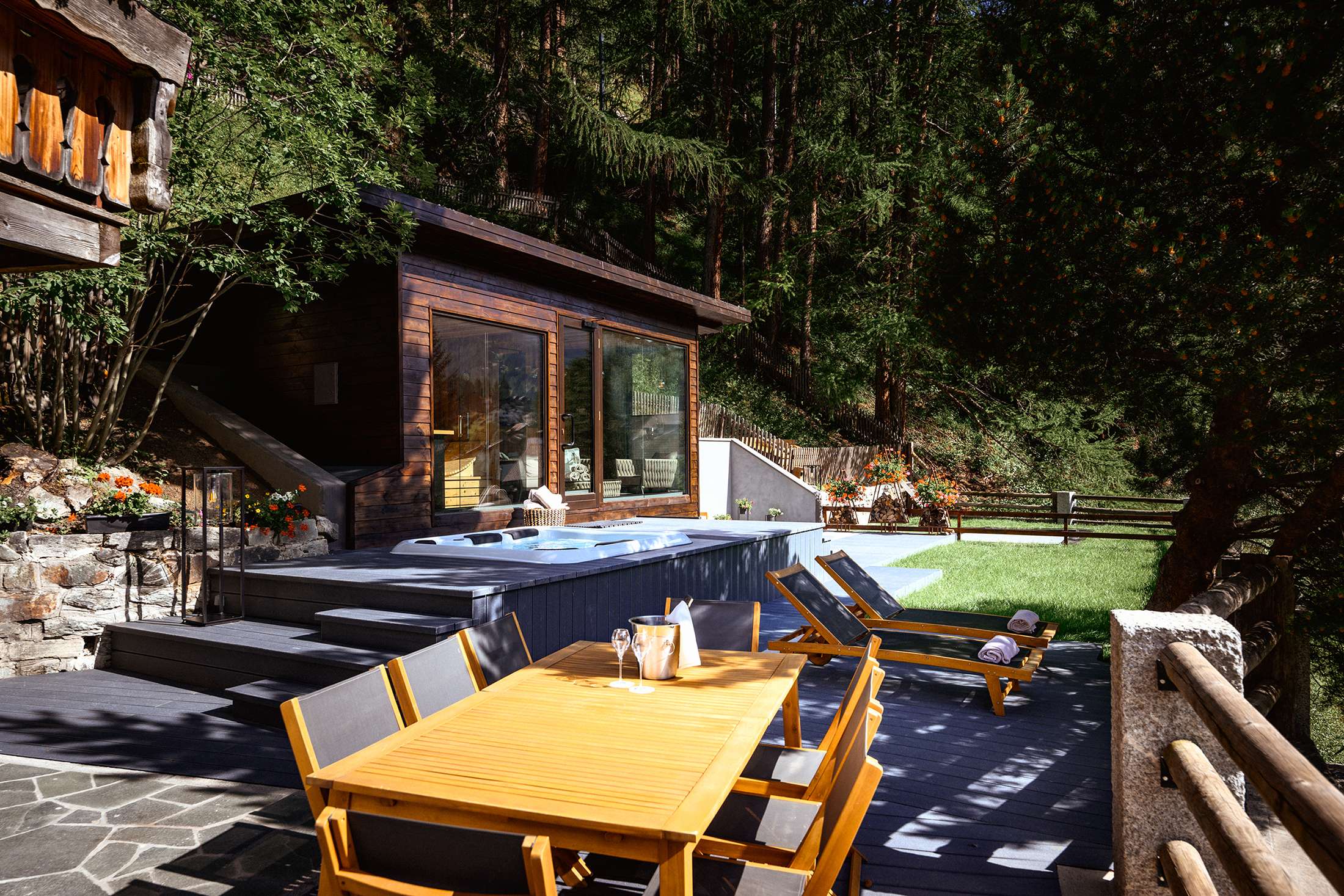 Holzterrasse mit Whirlpool, Sauna, Liegestühlen und Esstisch