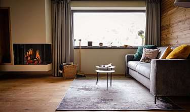 Gemütliches Wohnzimmer mit Kamin, Sofa, Couchtischen und großem Fenster