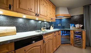 Helle Holzküche mit Arbeitsplatte, schwarzer Rückwand und integriertem Weinkühlschrank.