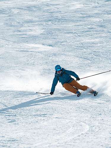Ein Skifahrer fährt eine steile, verschneite Abfahrt mit Schwung und Schneeaufwirbelung.