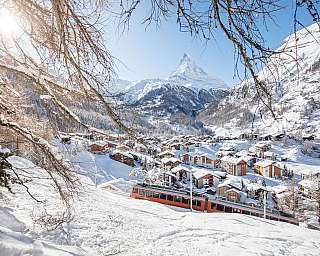 Village alpin enneigé avec le Matterhorn en arrière-plan et un train au premier plan
