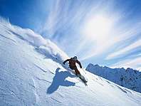 Un skieur descend une pente raide et enneigée sous un ciel bleu.